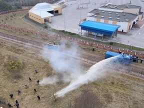 A still image, taken from a handout video released by the Belarusian Telegraph Agency, shows Polish law enforcement officers using a water cannon on migrants, who attempted to cross the Belarusian-Polish border at Bruzgi-Kuznica checkpoint in the Grodno region, Belarus, Tuesday, Nov. 16, 2021.