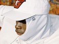 Person wearing a white Benetton hijab underneath a white baseball cap.