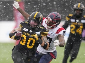 Hamilton Tiger-Cats defensive back Stavros Katsantonis (30) catches an interception as Montreal Alouettes wide receiver Eugene Lewis (87) tries to tackle him during first half CFL division semi-final football action in Hamilton, Ont., on Sunday, November 28, 2021.