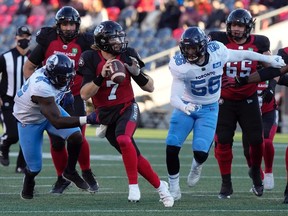 Redblacks quarterback Duck Hodges scrambles under pressure from Argonauts defensive linemen Cordarro Law, left, and Shane Ray during the first half of Saturday's game.