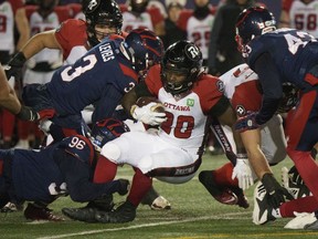 Redblacks running back Timothy Flanders is tackled by Alouettes defensive back Patrick Levels during the first quarter of Friday's game in Montreal.