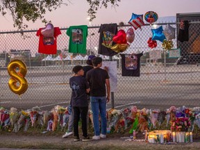 High school friends who attended the Travis Scott concert, Isaac Hernandez and Matthias Coronel watch Jesus Martinez sign a remembrance board at a makeshift memorial at the NRG Park grounds on Sunday, Nov. 7, 2021, where eight people died in a crowd surge at the Astroworld Festival in Houston.