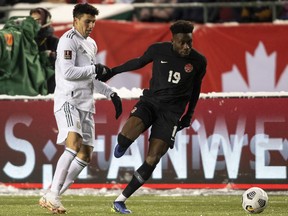 Canada's Alphonso Davies (19) and Mexico's Julio Cesar Domingguez Juarez (3) battle for the ball during a World Cup qualifier in Edmonton on Tuesday, Nov. 16, 2021.