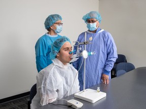 Fiona Smaill and research coordinator Emilio Aguirre demonstrate the use of the nebulizer with a volunteer.