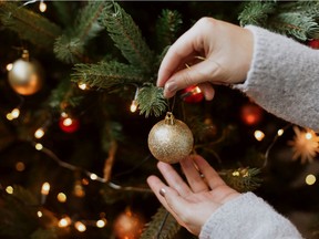 A person decorates a Christmas tree