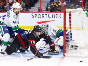 Drake Batherson (19) of the Senators is pushed into the crease by Kyle Burroughs (44) of the Canucks during a Dec. 1 game at the Canadian Tire Centre.