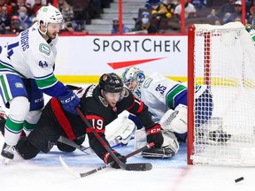 Kyle Burroughs of the Vancouver Canucks battles for the loose puck with Drake Batherson of the Ottawa Senators during the second period at the Canadian Tire Centre on Wednesday night.