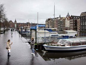 People stand in front of closed cruise ships in the centre of Amsterdam as Netherlands go back into lockdown to fight the Covid-19 pandemic on December 19, 2021.