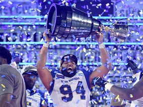 Winnipeg Blue Bombers defensive lineman Jake Thomas (94) lifts the Grey Cup trophy after defeating the Hamilton Tiger-Cats in the 108th Grey Cup at Tim Hortons Field, in December 2021