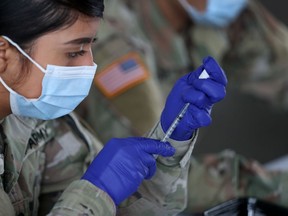 A U.S. Army soldier from the 2nd Armored Brigade Combat Team, 1st Infantry Division, prepares Pfizer COVID-19 vaccines to inoculate people at the Miami Dade College North Campus on March 09, 2021 in North Miami, Florida. (Photo by Joe Raedle/Getty Images)