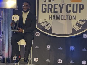 DeVonte Dedmon shows off a new suit and a smile his mother paid a lot of money for as the Redblacks star returner holds the CFL special teams player of the year award in Hamilton on Friday night.