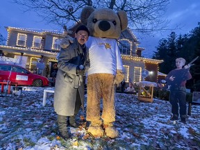 Shawn Turcotte poses with the CHEO Bear in front of the family's house, which has been decorated with a Home Alone theme with a goal of raising $100k for CHEO mental health services.