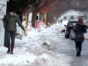 Two women walk along Fourth Avenue on Tuesday, Dec. 7, 2021, one navigating the icy sidewalk while the other opts for the road instead.