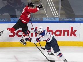 Canada’s Dylan Cozens (left) leaps as he is checked by USA’s Jake Sanderson at the world junior hockey championship last year.