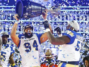 Winnipeg Blue Bombers Jackson Jeffcoat, left, and Jermarcus Hardrick hold up the Grey Cup in Hamilton. File photo