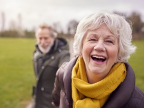Portrait Of Loving Senior Couple Enjoying Autumn Or Winter Walk Through Park Together