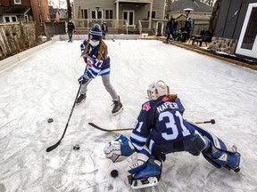 Riley Napier, 9, in goal, and Miyoko Hogeveen, 10, enjoy a backyard ice rink in Brampton, Ont. on Saturday, Jan. 8, 2022.