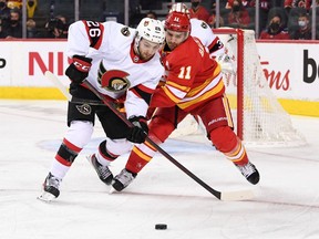 Ottawa Senators defenceman Erik Brannstrom (26) battles for the puck with Calgary Flames forward Mikael Backlund (11) during the third period at Scotiabank Saddledome. Senators won 4-1.