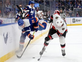 Scott Mayfield (24) of the New York Islanders and Alex Formenton (10) of the Ottawa Senators fight for the puck, Feb. 1, 2022.