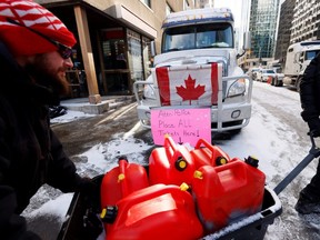 Demonstrators move fuel canisters down a street as truckers and supporters continue to protest COVID-19 vaccine mandates, in Ottawa, Tuesday, Feb. 15, 2022.