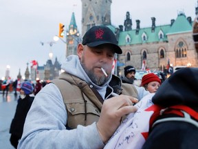 File photo/ Pat King, one of the organizers of the protest, signs a flag in front of Parliament Hill, February 16, 2022.