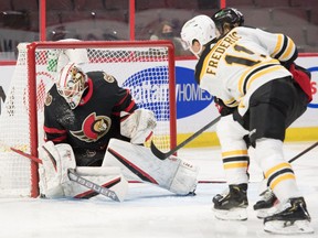Senators goalie Matt Murray (30) makes a save in front of Bruins centre Trent Frederic (11) Feb. 12, 2022.