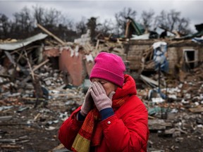 Irina Moprezova, 54, reacts in front of a house that was damaged in an aerial bombing in the city of Irpin, northwest of Kyiv, on March 13, 2022.