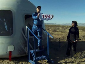 University of North Carolina professor Jim Kitchen shows a flag with "194" written on it, symbolizing his visits to 193 countries on Earth and his trip to sub-orbital space, as he emerges from the capsule of Blue Origin's rocket New Shepard after landing near Van Horn, Texas, March 31, 2022 in a still image from video.
