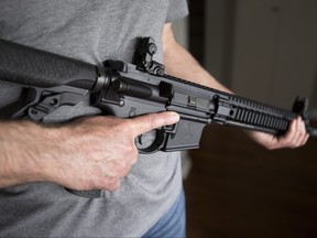 A restricted gun licence holder holds a AR-15 at his home in Langley, B.C. on May 1, 2020.