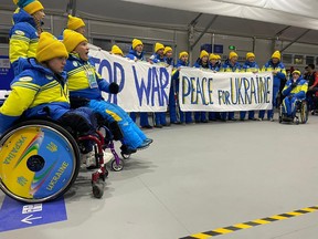 This handout photo taken and released on March 4, 2022 by the NPC Ukraine delegation shows delegation members holding banners to call for peace prior to the opening ceremony of the Beijing 2022 Winter Paralympic Games at the National Stadium in Beijing.