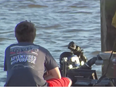 Diver in water with someone sitting on dock with back turned.