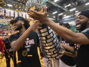 Carleton Ravens’ Biniam Ghebrekidan (left) and Lloyd Pandi hoist the trophy after defeating the Saskatchewan Huskies’ during the gold medal U Sports Men’s Final 8 Basketball Championship, in Edmonton Sunday. The win marks the third championship in a row and the 16th over 19 years. Jason Franson/THE CANADIAN PRESS