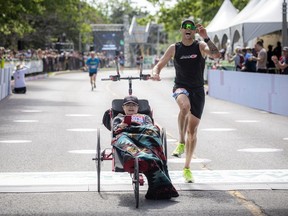Jean-Philippe Morand crosses the marathon finish line pushing his son, Victor Morand, at Tamarack Ottawa Race Weekend, Sunday, May 29, 2022.