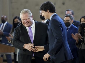 Prime Minister Justin Trudeau, right, shakes hands with Ontario Premier Doug Ford after reaching and agreement in $10-a-day child-care program deal in Brampton, Ont., on Monday, March 28, 2022.
