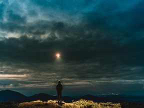 The UFO shines on a male standing on the mountain.