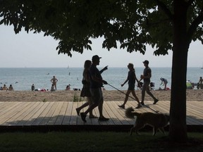 People stroll along the boardwalk in The Beaches neighbourhood in Toronto, July 25, 2021.