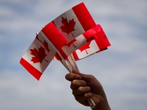 Files: A volunteer hands out flags on Canada Day