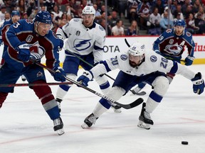 Jack Johnson of the Colorado Avalanche passes the puck past Nick Paul of the Tampa Bay Lightning during the third period in Game 2 of the 2022 NHL Stanley Cup Final at Ball Arena on June 18, 2022 in Denver.