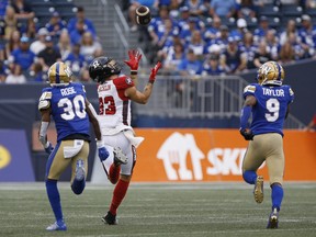 Ottawa Redblacks' Jaelon Acklin (23) reaches up for the pass, but doesn't make it as Winnipeg Blue Bombers' Winston Rose (30) and Nick Taylor (9) chase during the first half of CFL action in Winnipeg on Friday. 
John Woods
