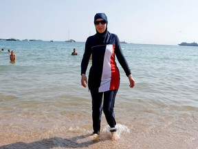 Karima, wearing a full-body burkini swimsuit, walks on a beach in Cannes.
