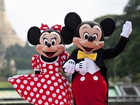 Walt Disney characters Mickey Mouse (R) and Minnie Mouse pose for photographs in front of the Shwedagon Pagoda in Yangon on September 25, 2014.