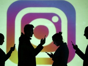 Silhouettes of mobile users are seen next to a screen projection of Instagram logo in this picture illustration.