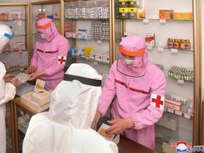 This picture taken and released from North Korea's official Korean Central News Agency on Tuesday, May 31, 2022 shows Korean People's Army medical personnel in protective clothing supplying medicines at a pharmacy in Pyongyang.