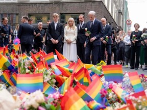 Norwegian Prime Minister Jonas Gahr Store (right), Crown Princess Mette-Marit of Norway (left) and Crown Prince Haakon of Norway (centre) lay flowers at a memorial at a crime scene on June 25, 2022, in the aftermath of a shooting outside pubs and nightclubs in central Oslo.