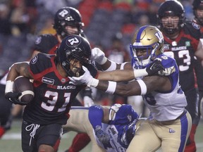 Ottawa Redblacks running back Devonte Williams is tackled by Winnipeg Blue Bombers defensive back Donald Rutledge Jr during the first half.