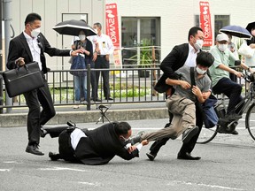 This image received from the Asahi Shimbun newspaper shows a man (centre R) suspected of shooting former Japanese prime minister Shinzo Abe being tackled to the ground by police at Yamato Saidaiji Station in the city of Nara on July 8, 2022. - Abe was pronounced dead on July 8, the hospital treating him confirmed, after he was shot at a campaign event in the city of Nara.