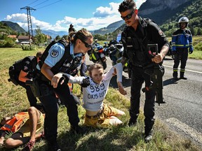 French gendarmes remove environmental protesters from the race route as their protest action temporarily immobilized the pack of riders during the 10th stage of the 109th edition of the Tour de France cycling race, 148,1 km between Morzine and Megeve, in the French Alps, on July 12, 2022.