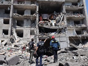 A war crimes prosecutor (centre), a rescuer (right) and a civilian look at a destroyed building that was hit by a missile strike in the Ukrainian town of Sergiyvka, near Odesa, Friday, July 1, 2022.