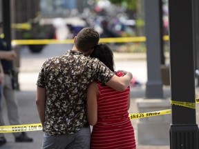 Brooke and Matt Strauss, who were married Sunday, look toward the scene of the mass shooting in downtown Highland Park, Ill., a Chicago suburb, after leaving their wedding bouquets near the scene of Monday's mass shooting, Tuesday, July 5, 2022.