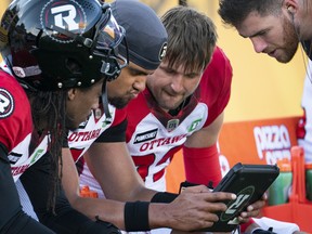 Ottawa Redblacks quarterback Caleb Evans, centre, looking at game replays during first half CFL football game action against the Hamilton  Tiger Cats in Hamilton, Ont. on Saturday, July 16, 2022.